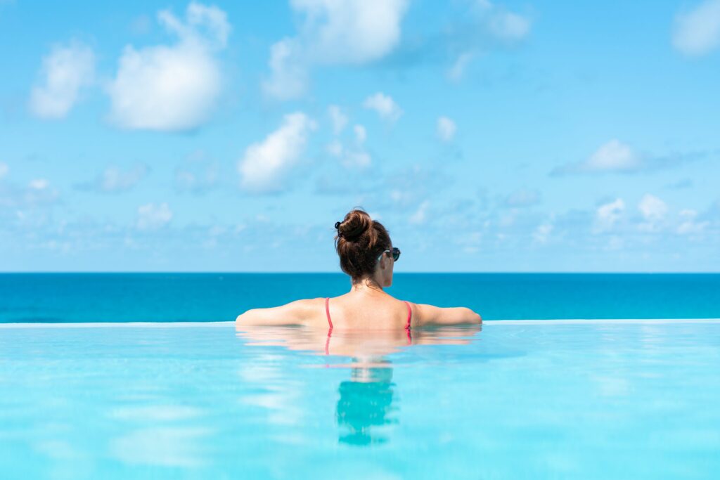 woman relaxing on vacation in infinity edge swimming pool
